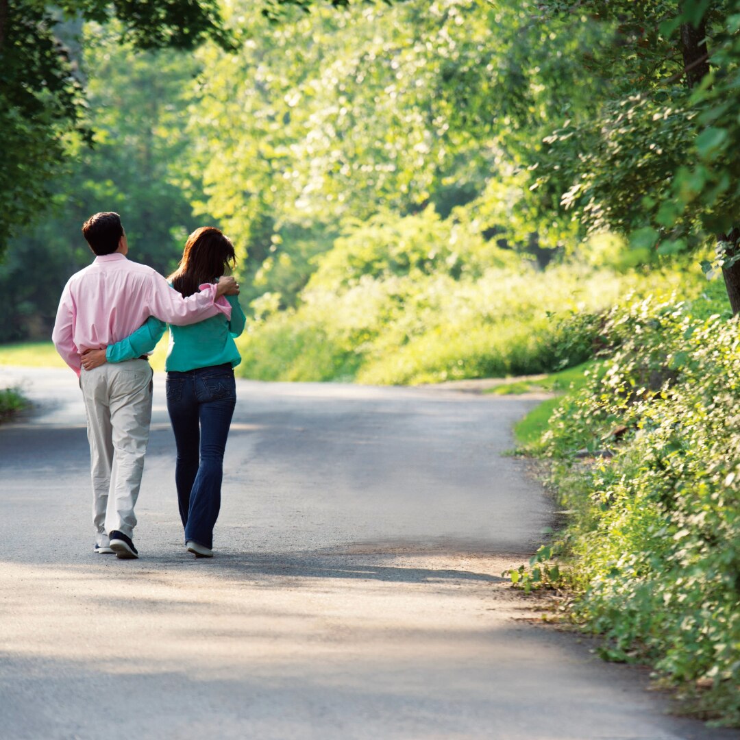 Man and woman walking down a windy path through the woods.