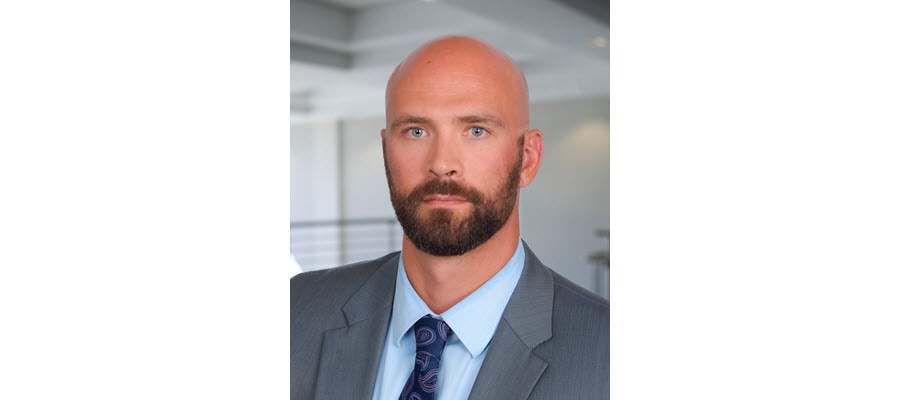 Formal headshot of a bald man in a suit.