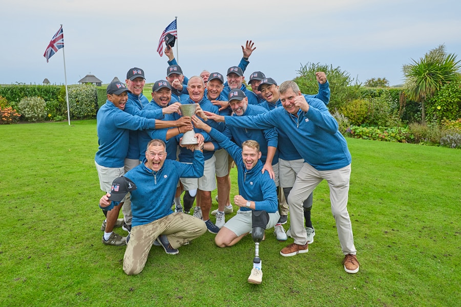 A group of menpose jubilantly with a trophy on a golf course.