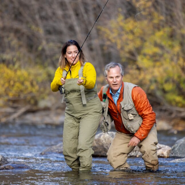 Woman and Father fly fishing in a river.