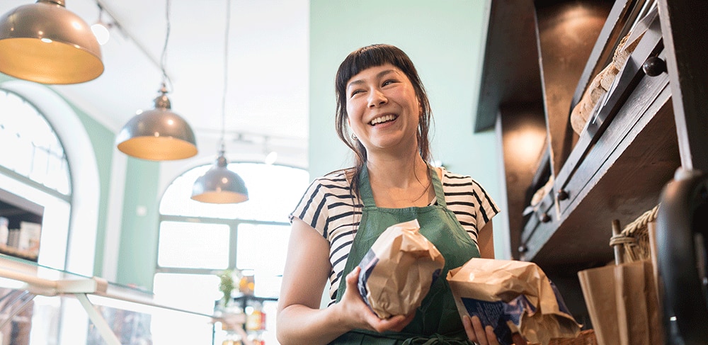 Smiling shopowner holding bags of food