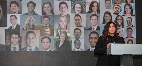 A speaker presenting against a gender collage backdrop.