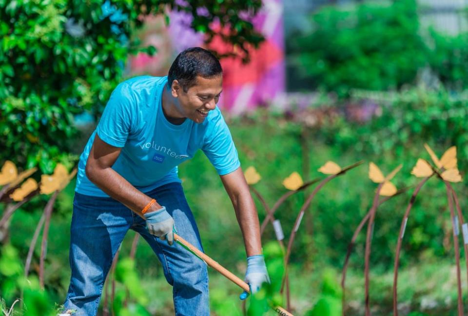 Schwab volunteer raking a garden.