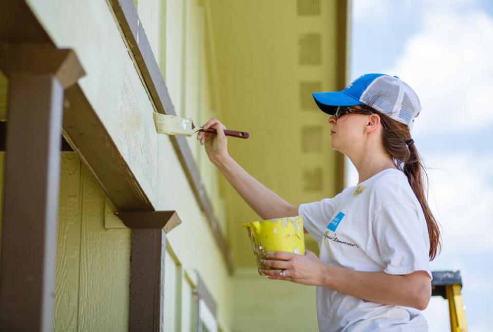 Schwab volunteer painting outside a building