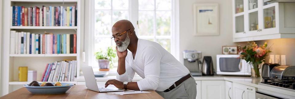 Man looking at his laptop in his kitchen.