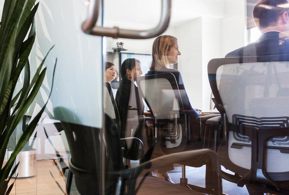 People in a meeting seen through a window.