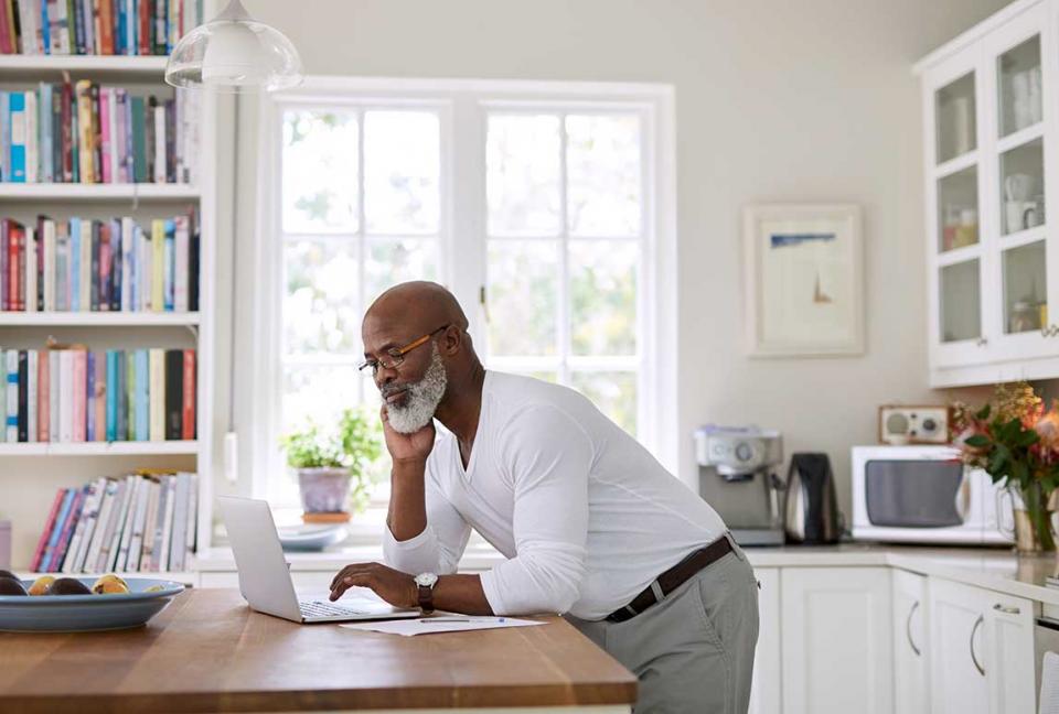 Man looking at his laptop in his kitchen.