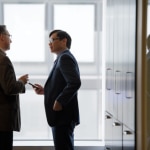 two men in conversation in a hallway