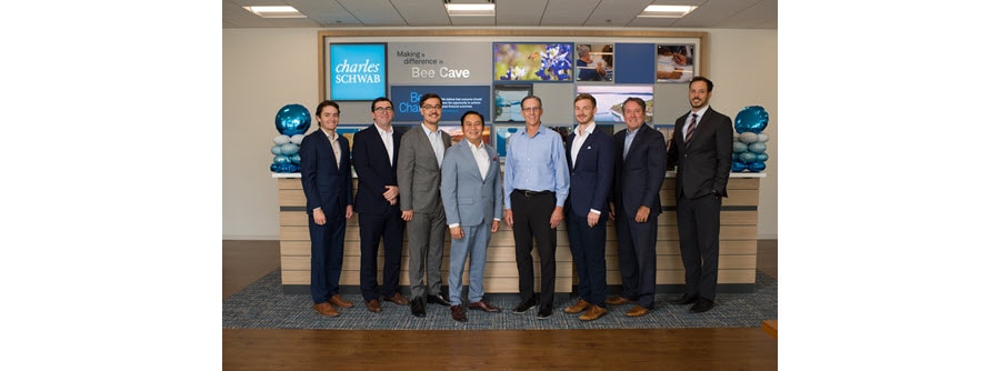 A group of men pose for a photo inside a Schwab branch.